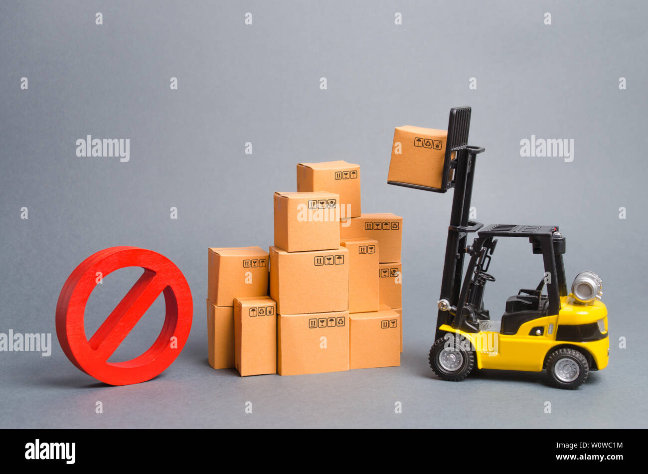 Gelbe Gabelstapler truckraises eine Box über einen Stapel Kisten und ein rotes Symbol Nr. Embargo Handelskriege. Beschränkung bei der Einfuhr von Waren, Verbot von Exp Stockfoto