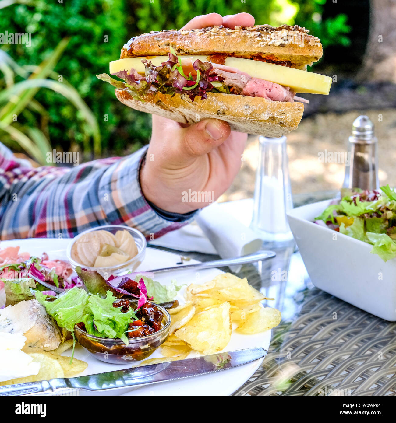 Mann mit einem frischen Salat Plowmans Brötchen gefüllt mit Käse, Gurke und Schinken Stockfoto