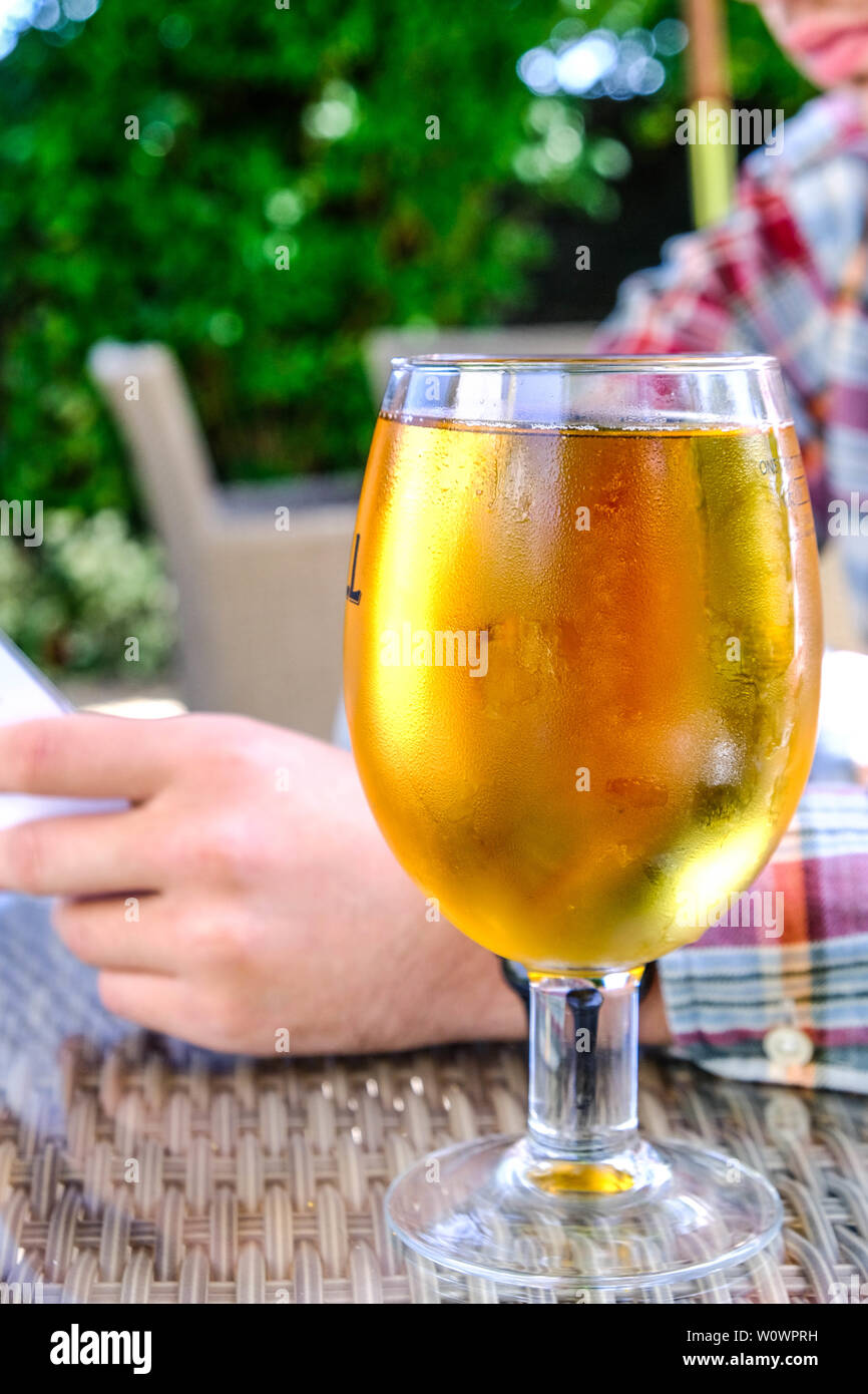 Glas kalten Apfelsaft auf einem Tisch mit einem Mann Lesen einer Speisekarte Stockfoto