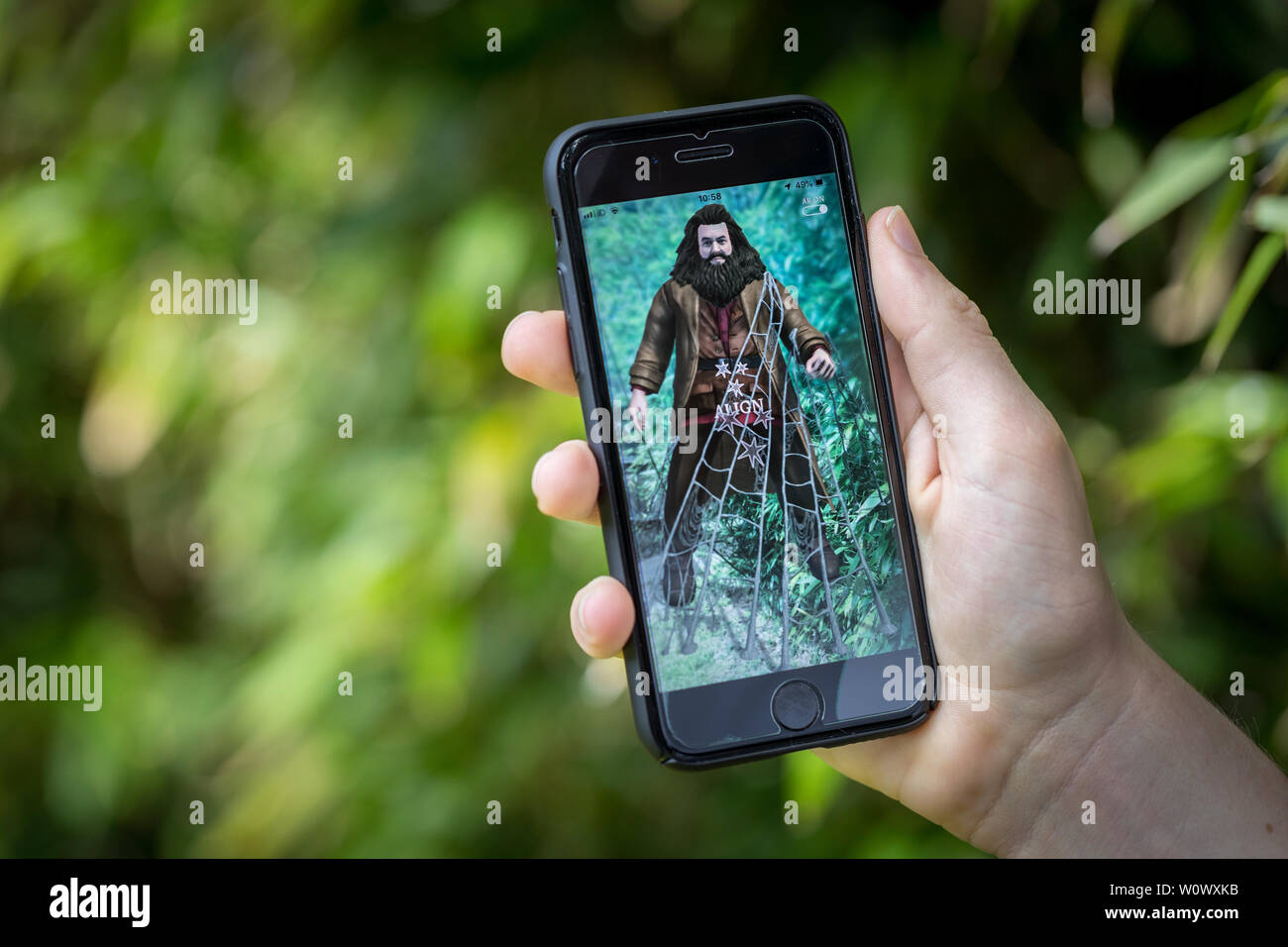 Ein Teenager spielen Der neue Harry Potter Zauberer Unite Apps auf seinem iPhone im Park Stockfoto