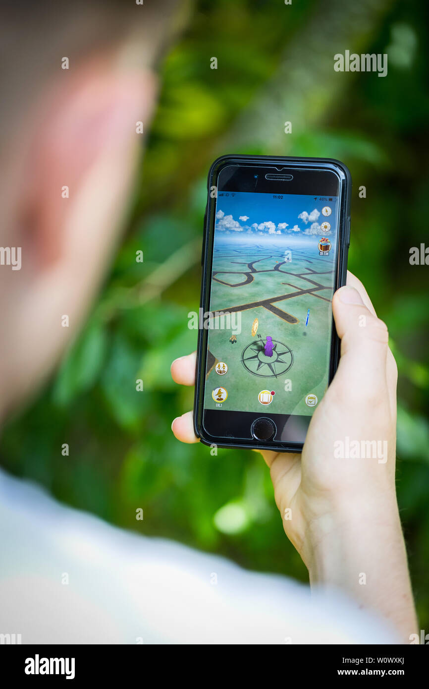 Ein Teenager spielen Der neue Harry Potter Zauberer Unite Apps auf seinem iPhone im Park Stockfoto