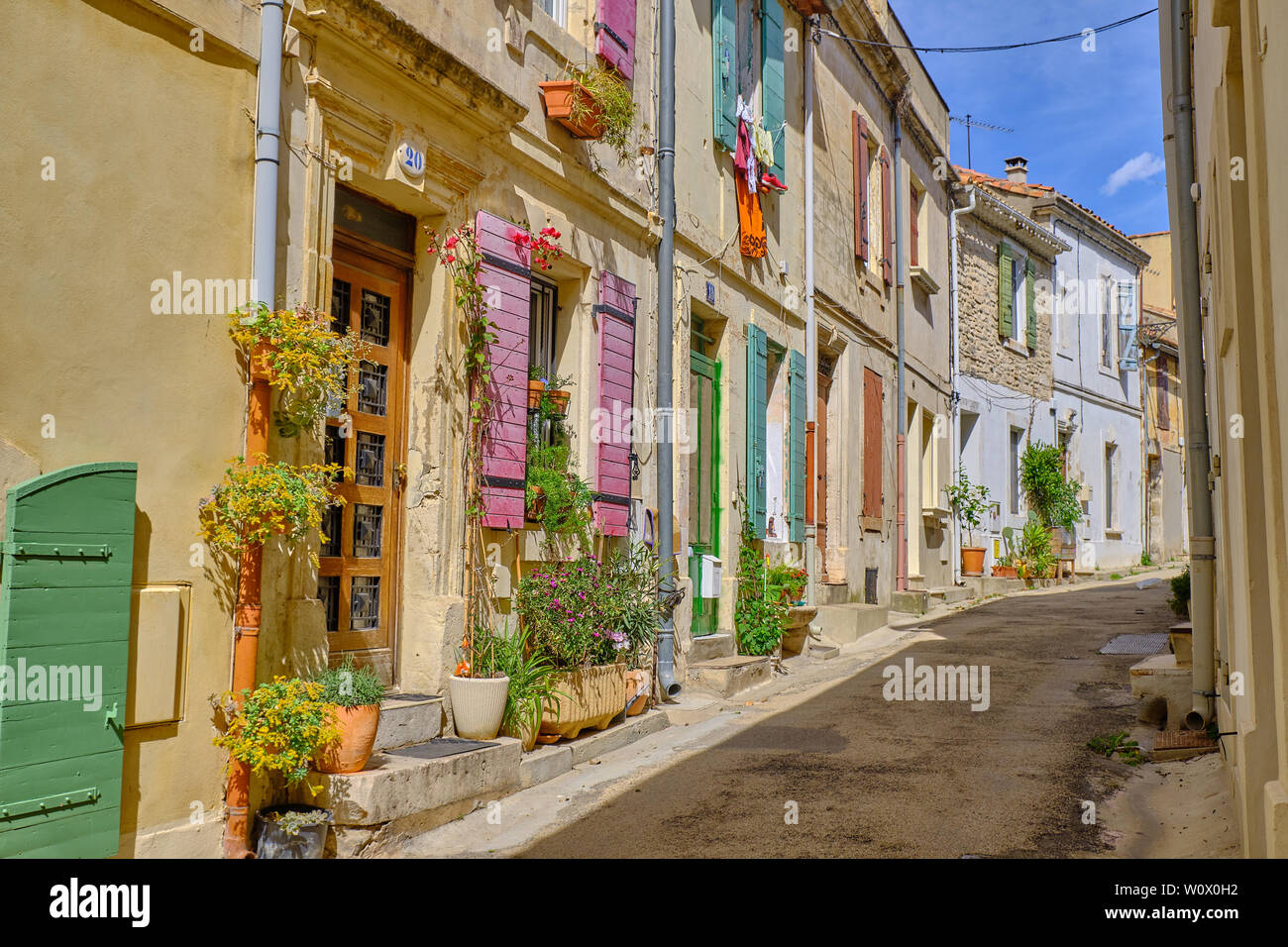 Typische Straße der Altstadt von Arles, mit bunten Fensterläden und Türen, Hängepflanzen und Wäscheservice an einem sonnigen Tag. Arles, Frankreich Stockfoto