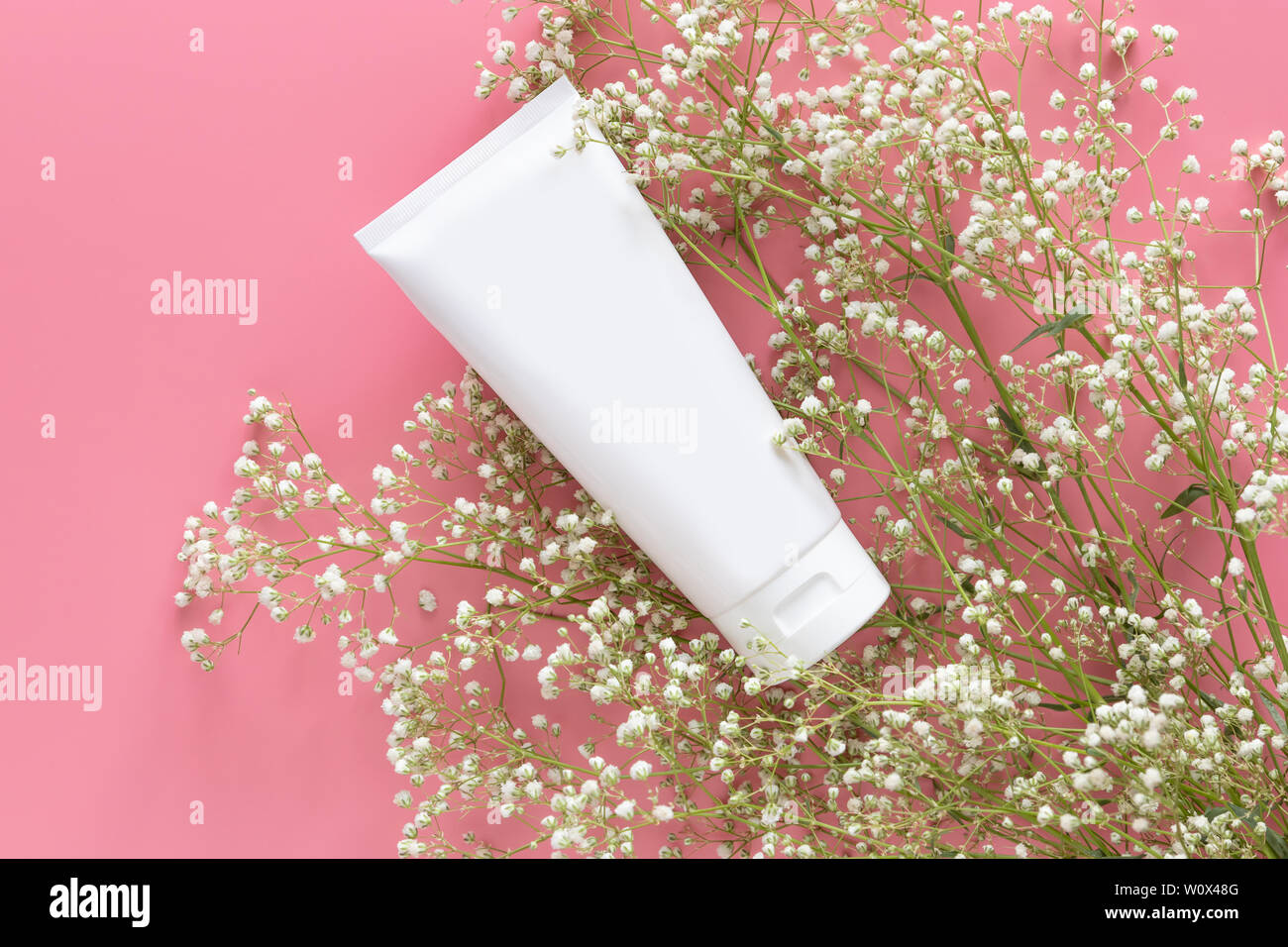Kosmetischer Natur organische Hautpflege Kosmetik Konzept. Weiße Tube Container mit leeres Etikett für das Branding Verpackung mock up, mit weißen Blumen o Dekorieren Stockfoto