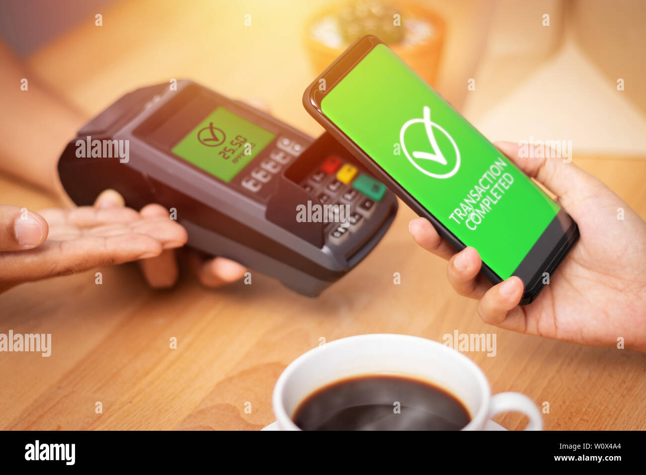 Bargeldlose Gesellschaft, Kunde zahlt Rechnung durch das Smartphone mit der NFC-Technologie am Point of Sale Terminal in Cafe. Mobile Digital Wallet Technologie con Stockfoto