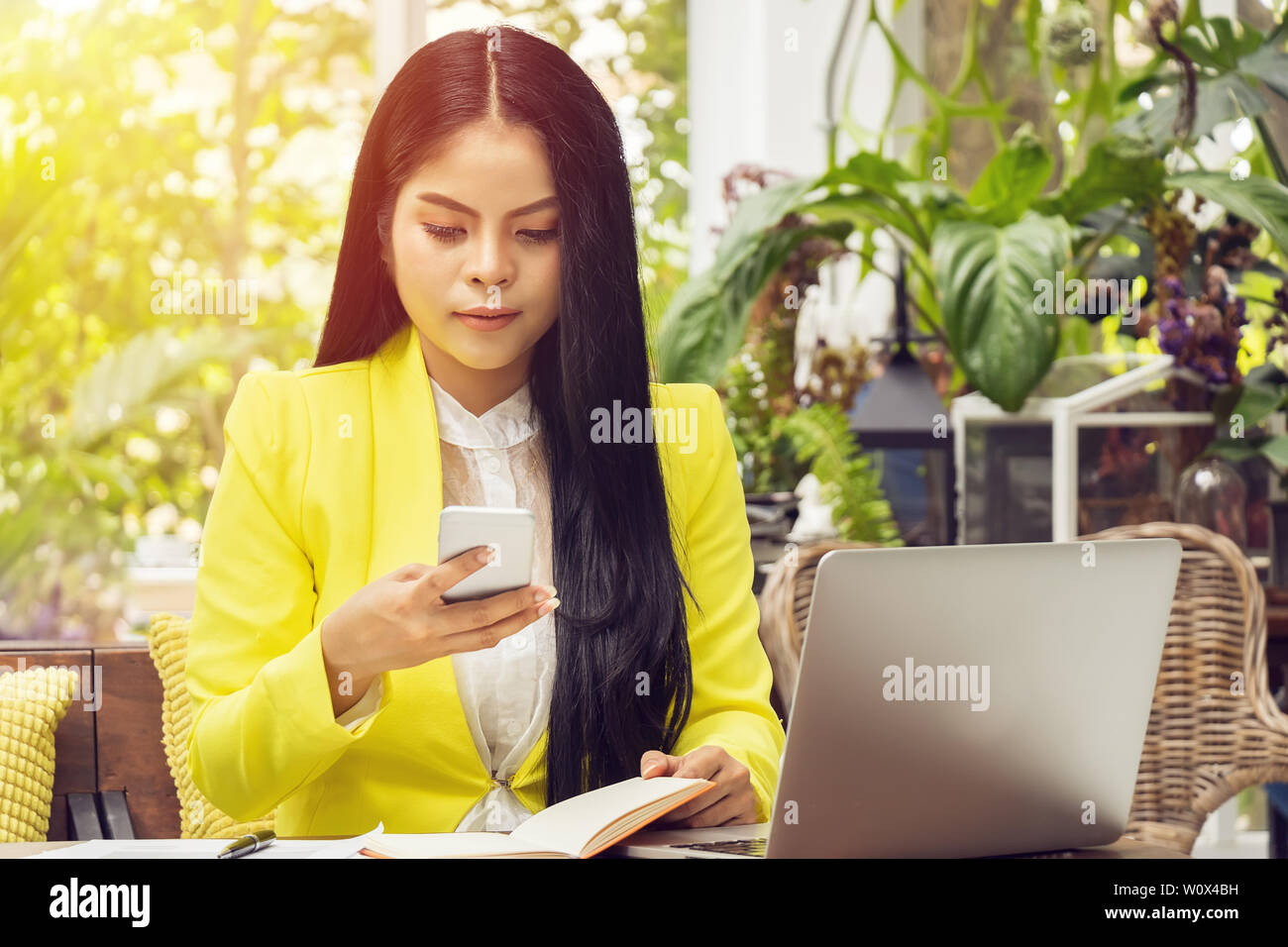 Porträt der Schönen und zuversichtlich Asian Business Frau sitzen vor dem Notebook Laptop und Telefon für Termin update am Arbeitsplatz Stockfoto