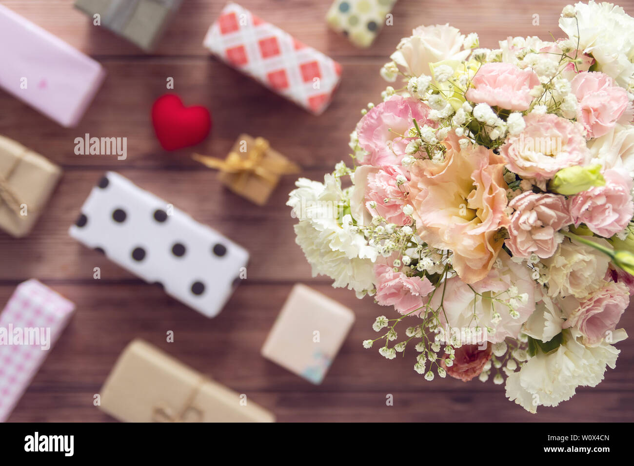 Flach der Blumenstrauß aus schöne romantische frische Blumen mit bunten Geschenkbox auf hölzernen Hintergrund vorhanden, Ansicht von oben Stockfoto