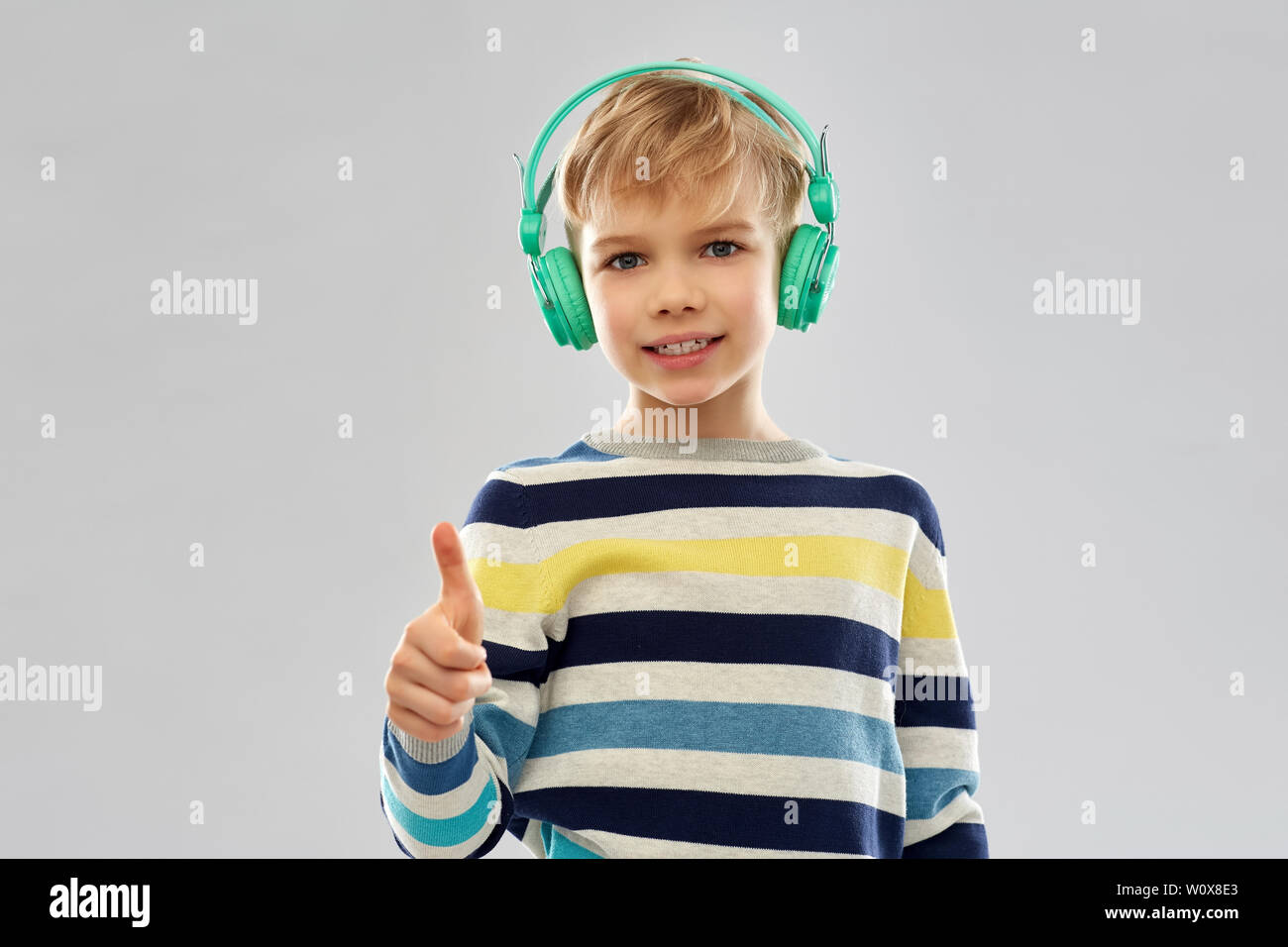 Junge in Kopfhörer mit Daumen hoch Stockfoto