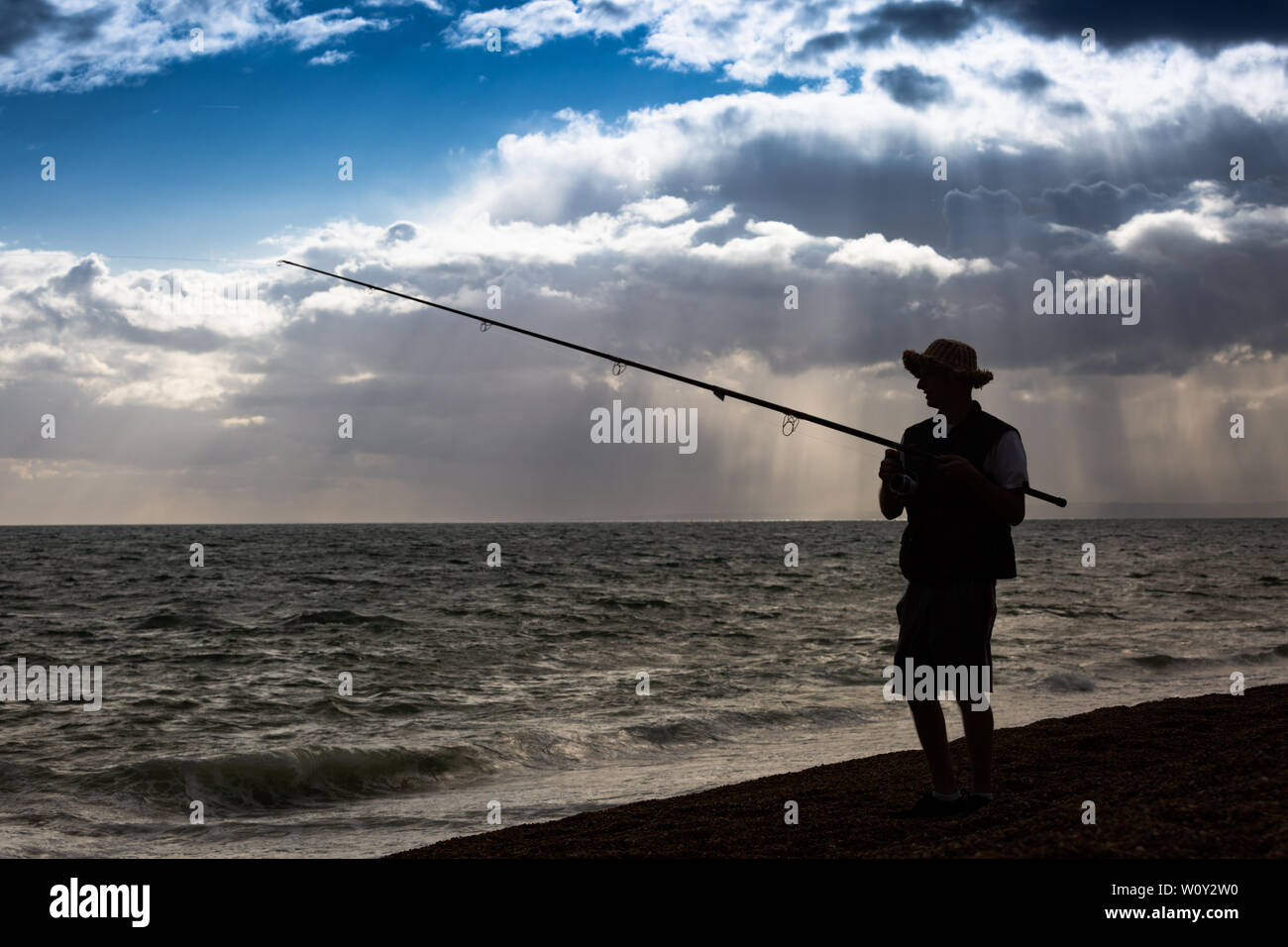 Junger Mann angeln auf einem Kieselstrand, Chesil, Portland, Dorset UK Stockfoto