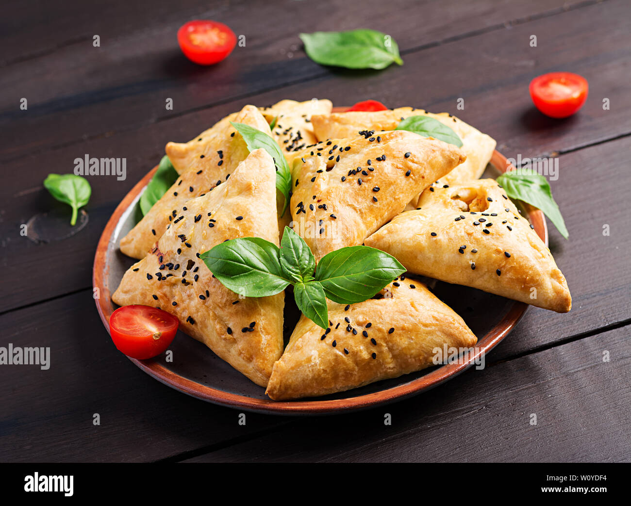 Asiatische Küche. Samsa (Samosa) mit hühnerfilet und grüne Kräuter auf Holz- Hintergrund. Stockfoto