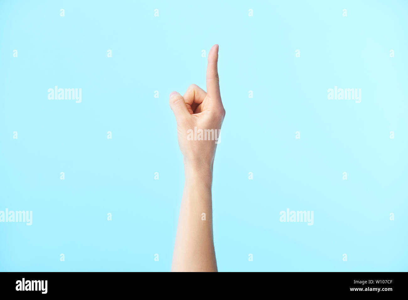 Menschliche Hand zeigt die Nummer eins, auf blauem Hintergrund isoliert Stockfoto