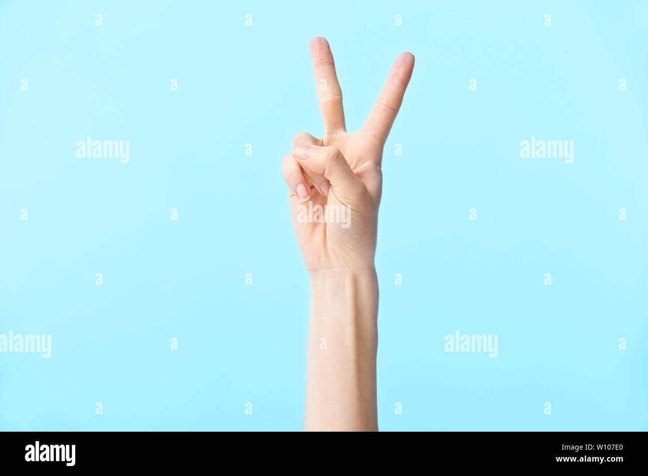 Menschliche Hand zeigt die Nummer zwei, auf blauem Hintergrund isoliert Stockfoto