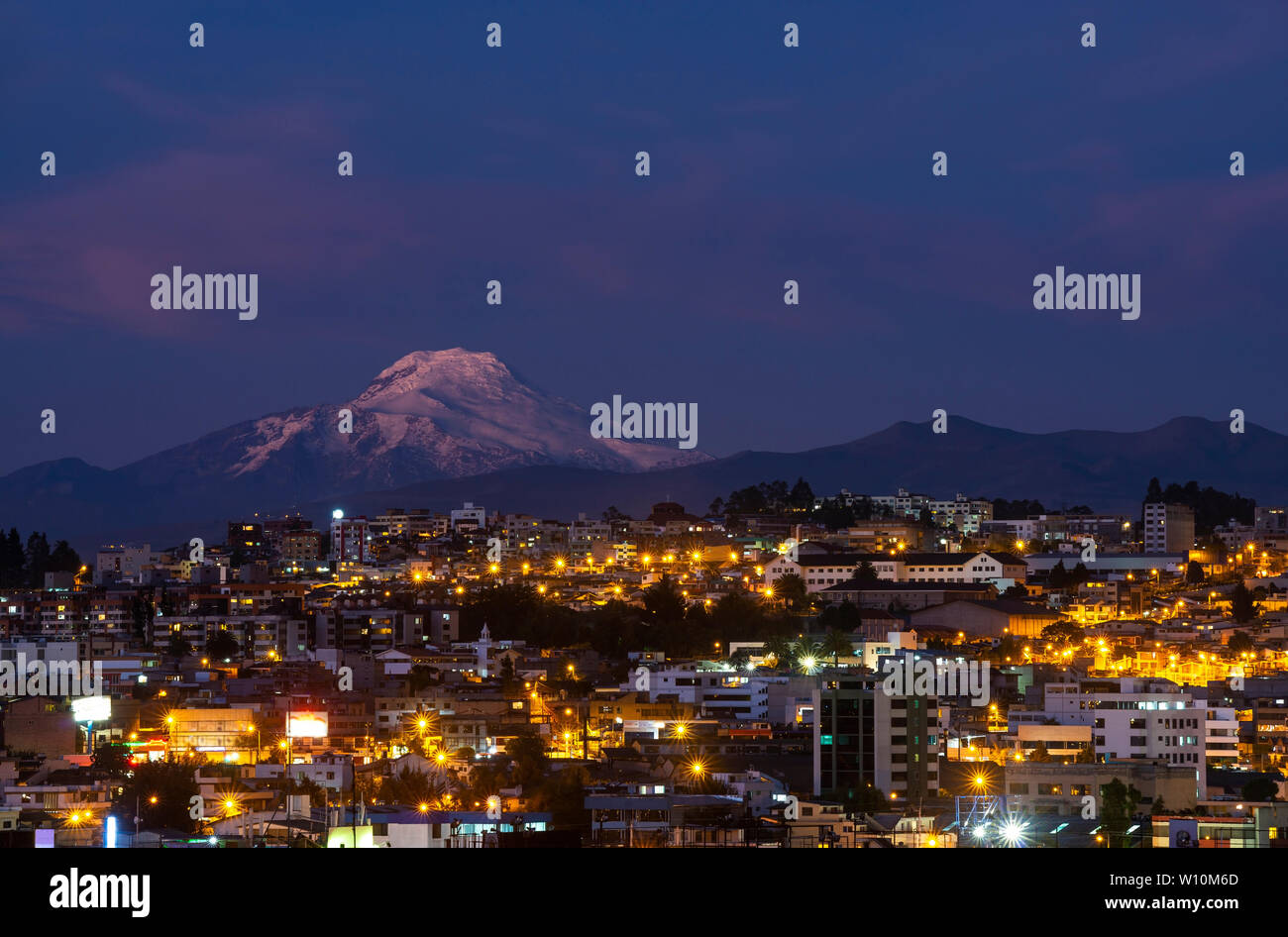 Stadtbild von Quito bei Nacht mit der beeindruckende Vulkan Cayambe, Anden, Ecuador, Südamerika. Stockfoto