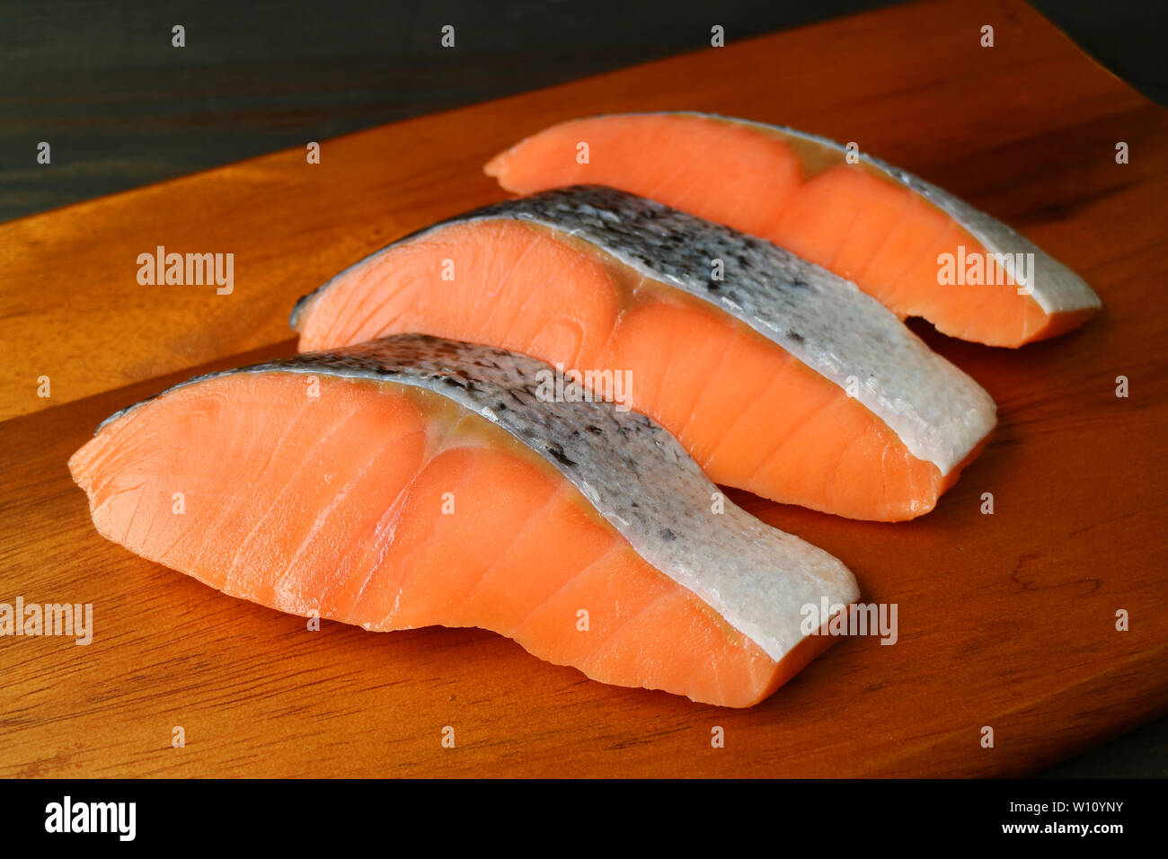 Drei Stücke geschnittenen frischen, rohen Lachs auf einer hölzernen Schneidebrett Stockfoto