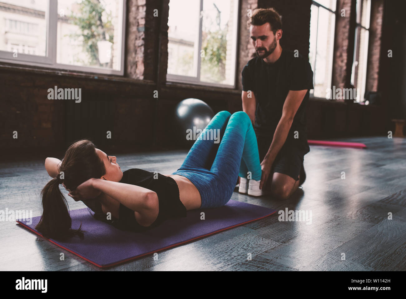 Personal Trainer hilft ein Mädchen mit der Turnhalle Übungen Stockfoto