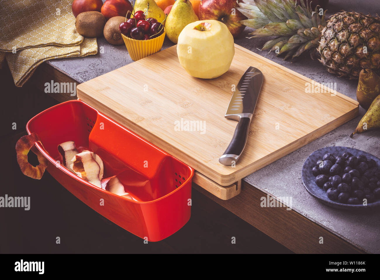 Schneidbrett mit roten Abfallbehälter mit frischen Früchten Hintergrund. Gesunde Ernährung vegane Rohkost Konzept. Stockfoto
