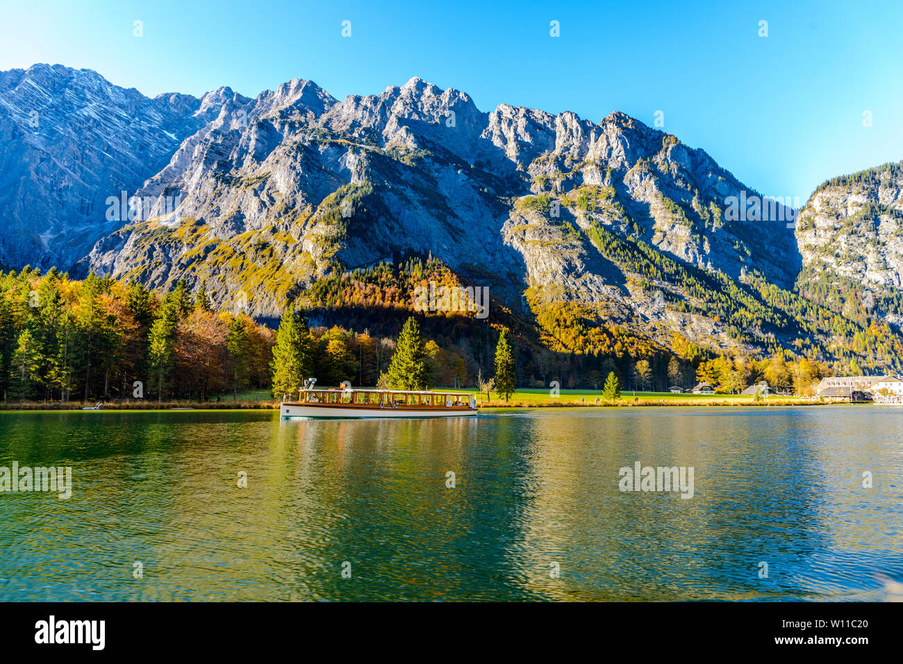 Blick auf Konigssee (Königssee, Königsee, Königssee, Koenigssee, Konigsee, Konig) See im Herbst, mit einem Boot in der Nähe der Kirche St. Bartholomäus (Bartholoma Stockfoto