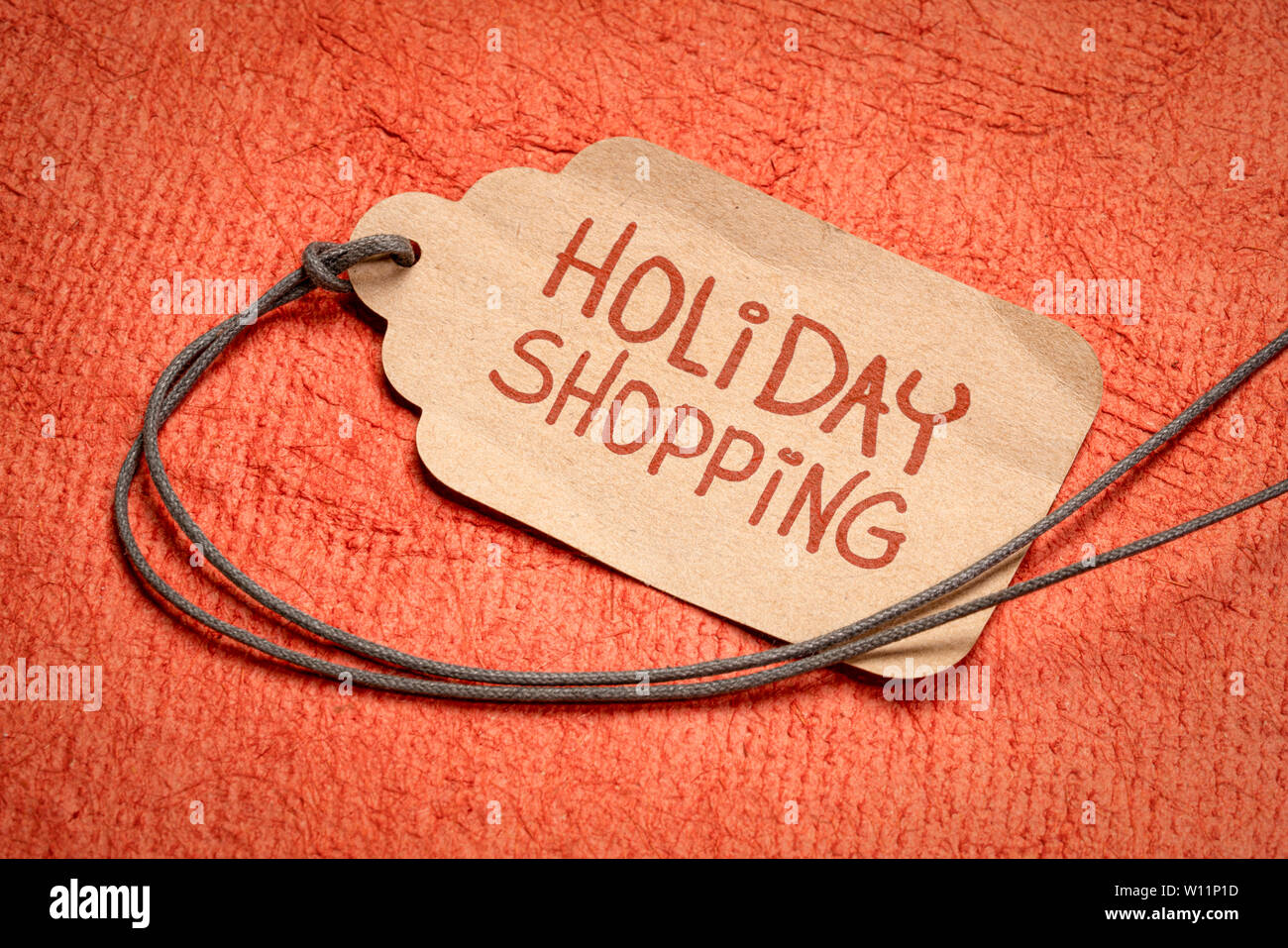 Holiday Shopping Zeichen - ein Preisschild mit einem String gegen Strukturierte handgeschöpftem Papier Stockfoto