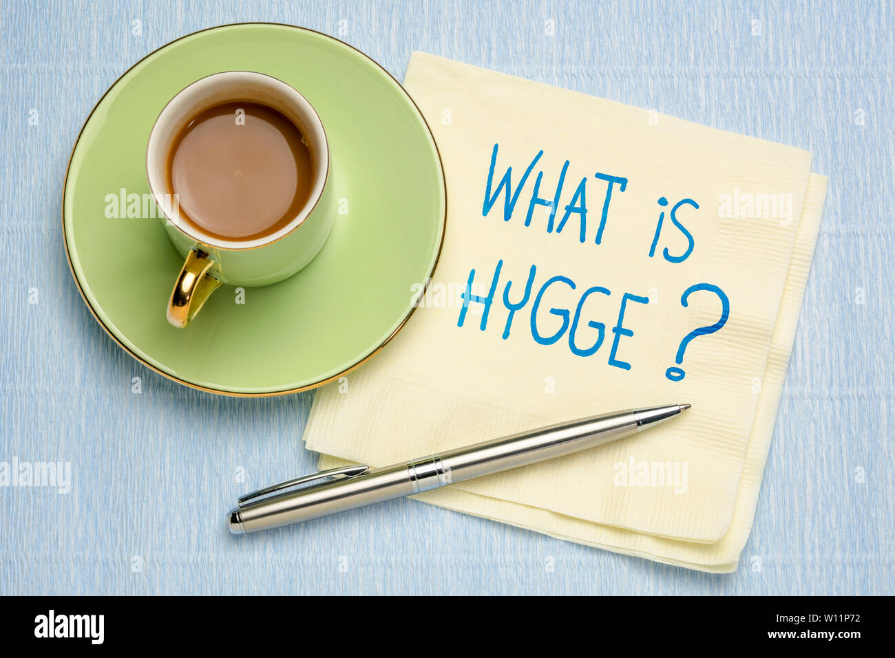 Was ist hygge? Handschrift auf eine Serviette mit einer Tasse Kaffee. Stockfoto