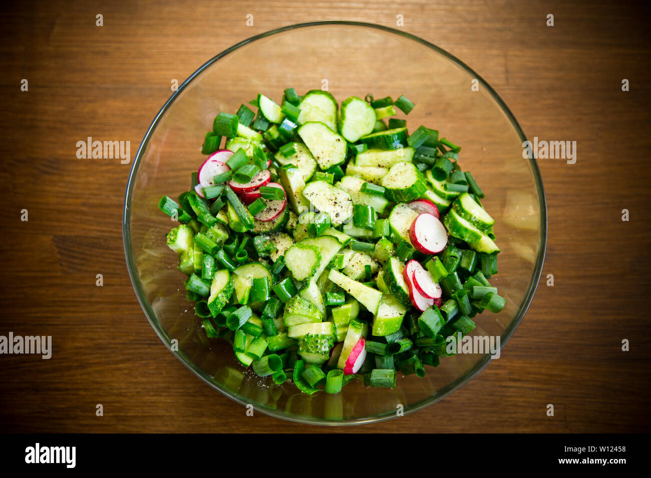 Frischer Salat mit Gurken und Grüns in einen Teller auf einem Holztisch Stockfoto