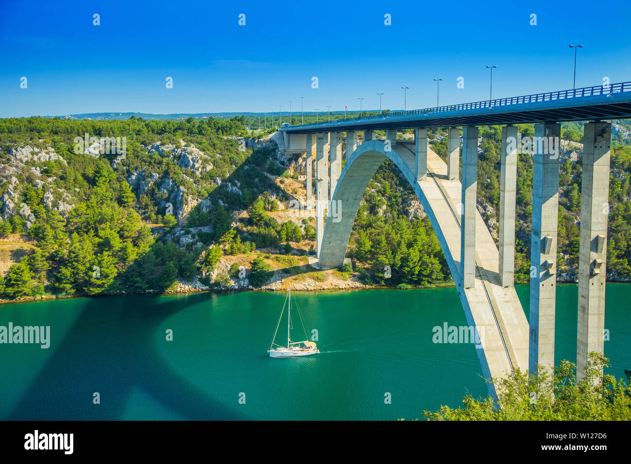 Antenne panorama Blick von Brücke auf Autobahn über Fluss Krka in tiefen Canyon in Kroatien und Segelboot vorbei unter. Schöne Landschaft. Stockfoto
