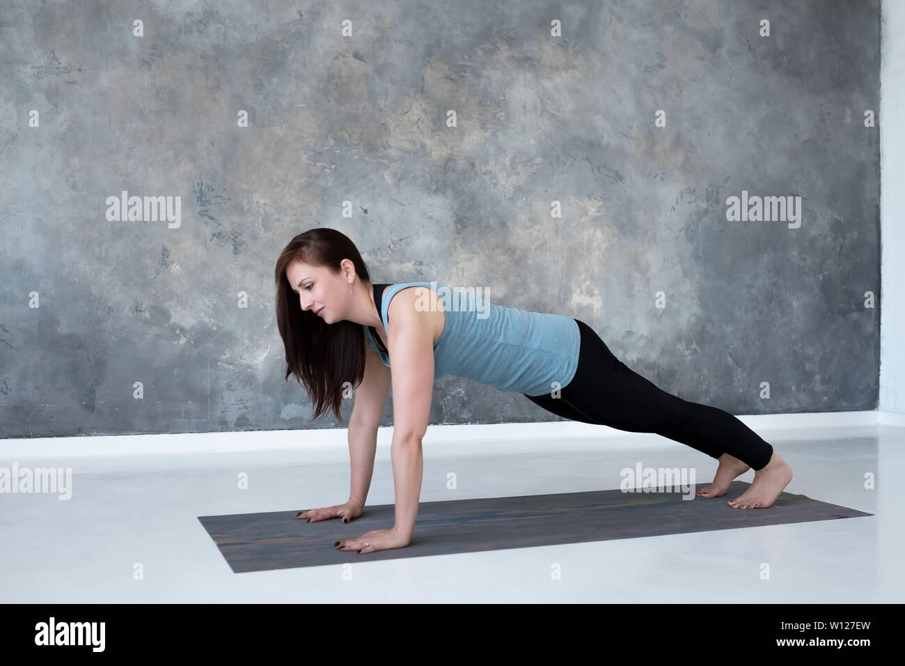 Junge Frau Üben Yoga, oder drücken Sie die Taste Push-ups ups Übung Liegestütz. Stockfoto