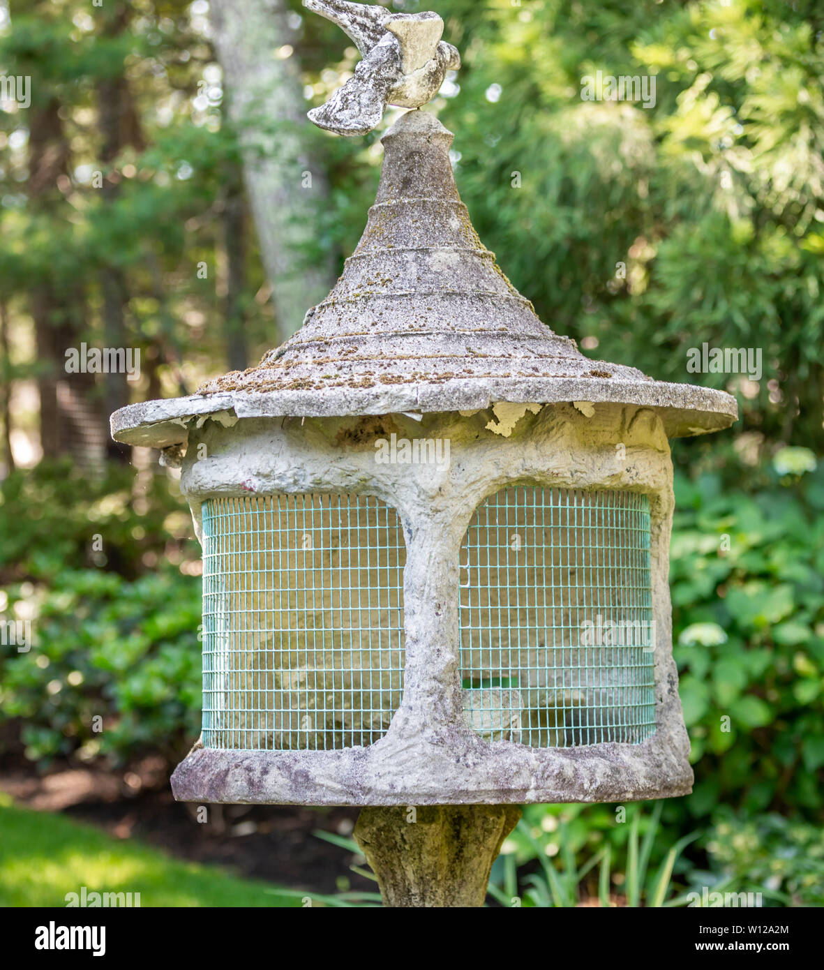 Konkrete Vogelkäfig mit Vogel auf der Oberseite in einem Garten Stockfoto