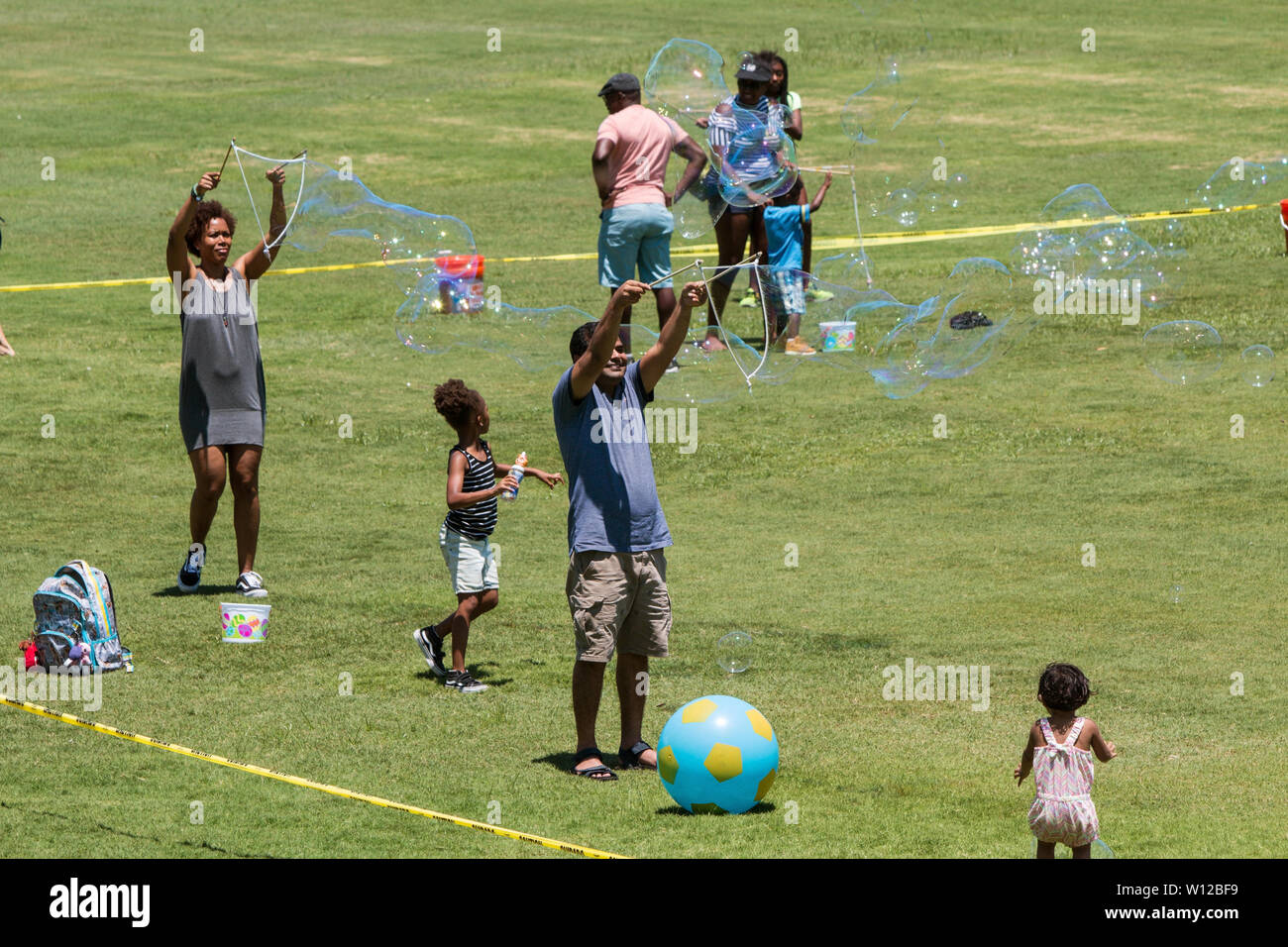 Eltern bilden riesige Blasen, indem das zauberstäbe mit Seifenwasser am Atlanta Eis Festival in Piedmont Park am Juli 28, 2018 in Atlanta, GA. Stockfoto