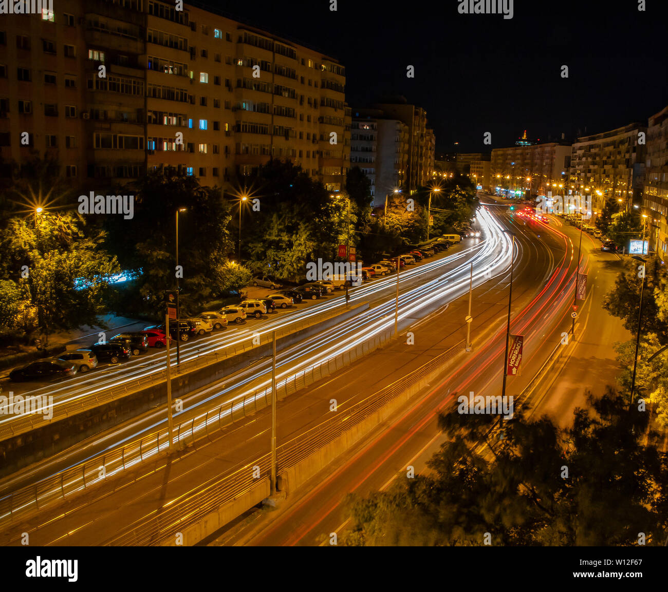 Bukarest, Rumänien - 14. August 2018: Leichte Spuren von Autos neben der kommunistischen Ära Gebäude an einem der rumänischen Hauptstadt breiten Boulevards in der Nacht Stockfoto