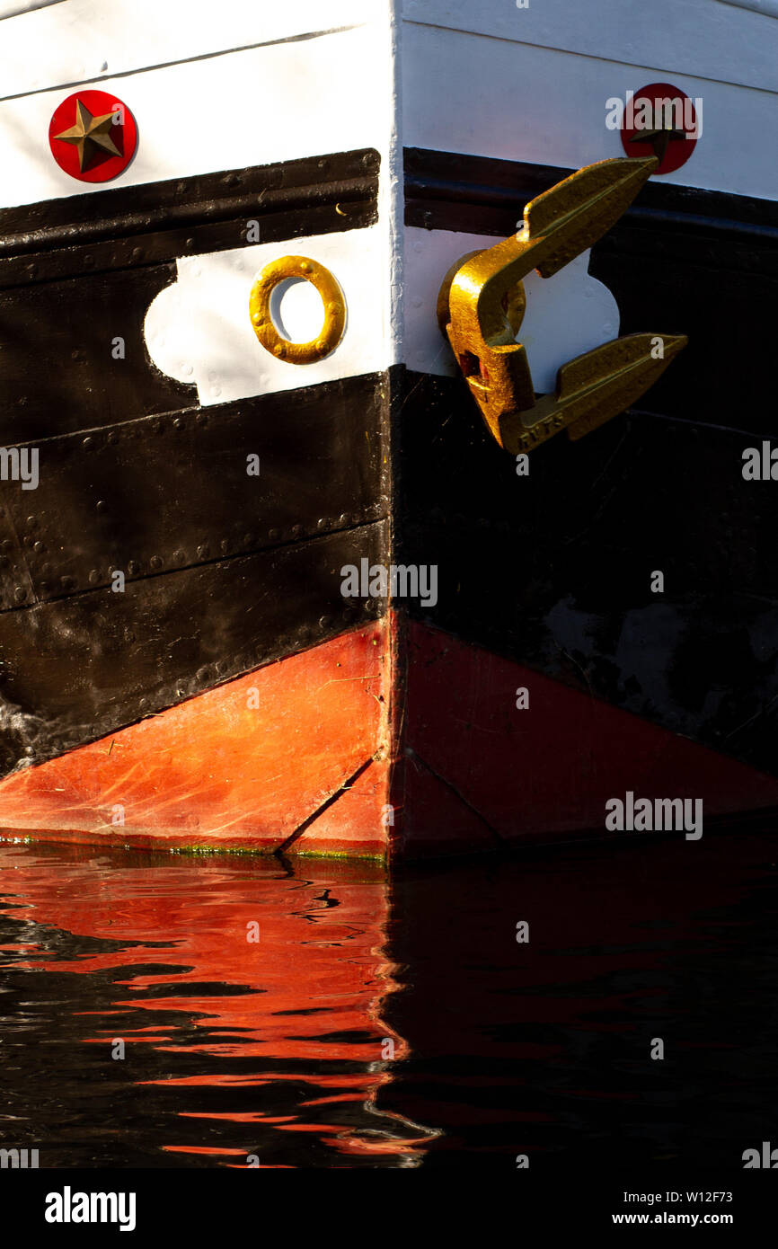 Auffällig lackierte Front von einem holländischen Schiff oder Boot mit goldenen Anker oberhalb der Wasserlinie sowie eine rote Kiel Stockfoto