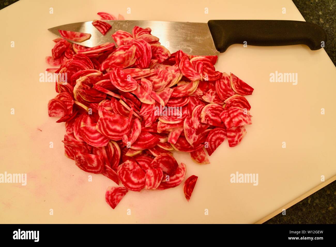 In Scheiben geschnitten, um Frische, helle rote Chioggia Rote Rüben (Rote Beete) auf einem weißen Schneidebrett mit Messer, Wisconsin, USA. Stockfoto