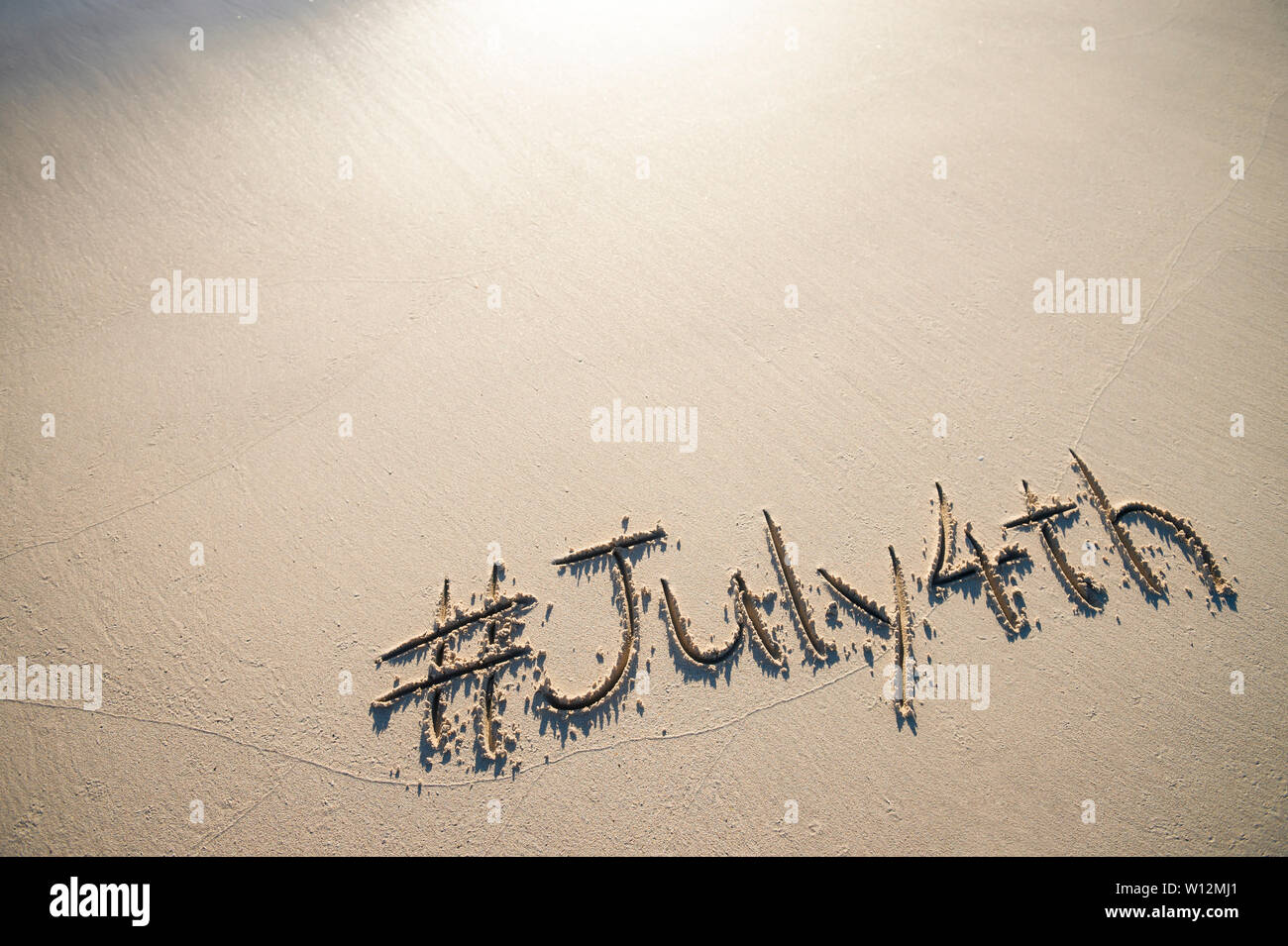 Moderne Nachricht für den 4. Juli amerikanischen Feiertag mit einem Social Media - freundliche hashtag in Glatten sand Geschrieben am Strand Stockfoto