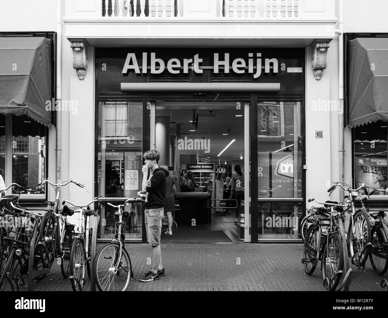 Haarlem, Niederlande - 20.August 2018: Vorderansicht des Albert Heijn niederländische Supermarktkette, 1887 in Oostzaan, Niederlande, gegründet auf Kruisstraat 10 Straße mit jungen Mann Schwarz und Weiß Stockfoto