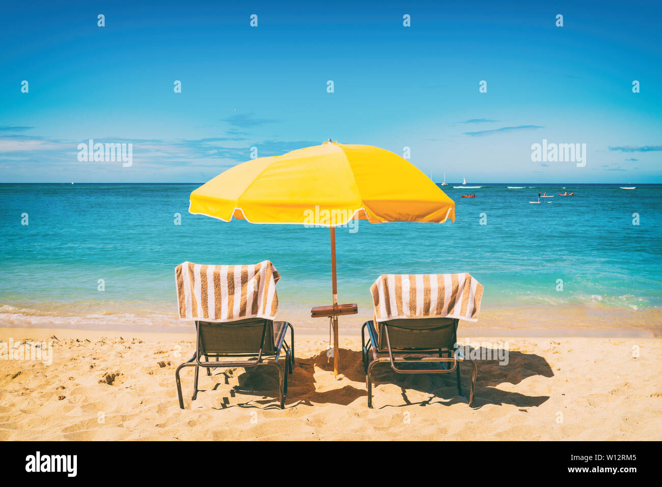 Urlaub am Strand Liegestühle unter Sonnenschirmen Ferienhäuser Hintergrund. Sommer tropisches Reiseziel. Stockfoto