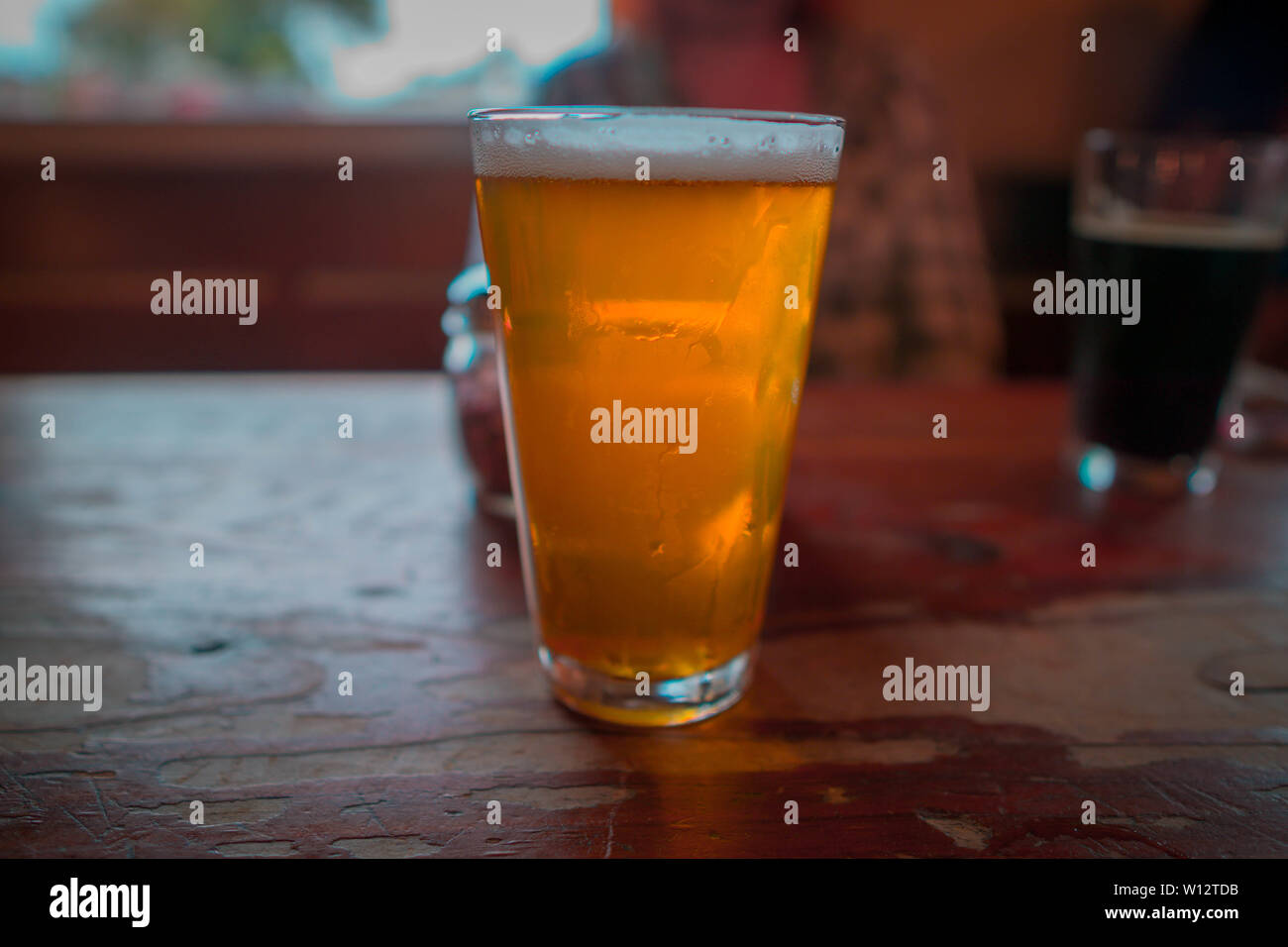 Golden Ale Bier mit einer Person im Hintergrund Stockfoto