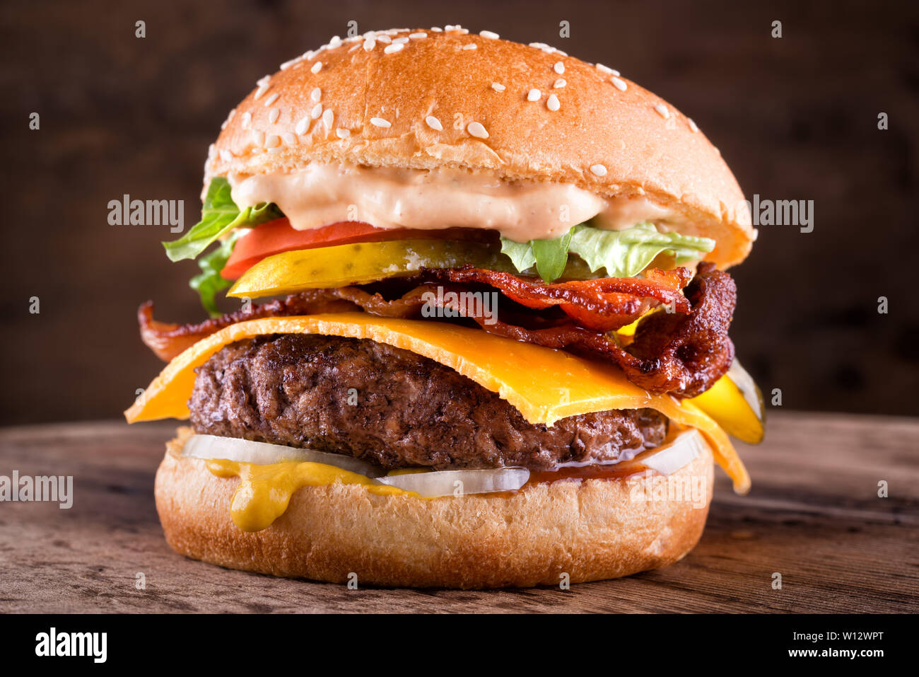 Eine köstliche hausgemachte bacon Cheeseburger mit echten Cheddar Käse, Salat, Zwiebeln, Tomaten, Gurken, Senf, Ketchup und Burger Sauce. Stockfoto