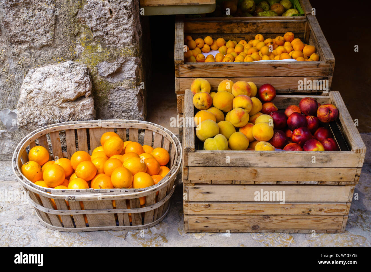 Wahl von reifen Orangen, Pfirsiche, Nektarinen, Pflaumen und Birnen in Holzkisten und einem Korb an einem Lebensmittelmarkt - Frontalansicht, horizontalen Landschaft Stockfoto