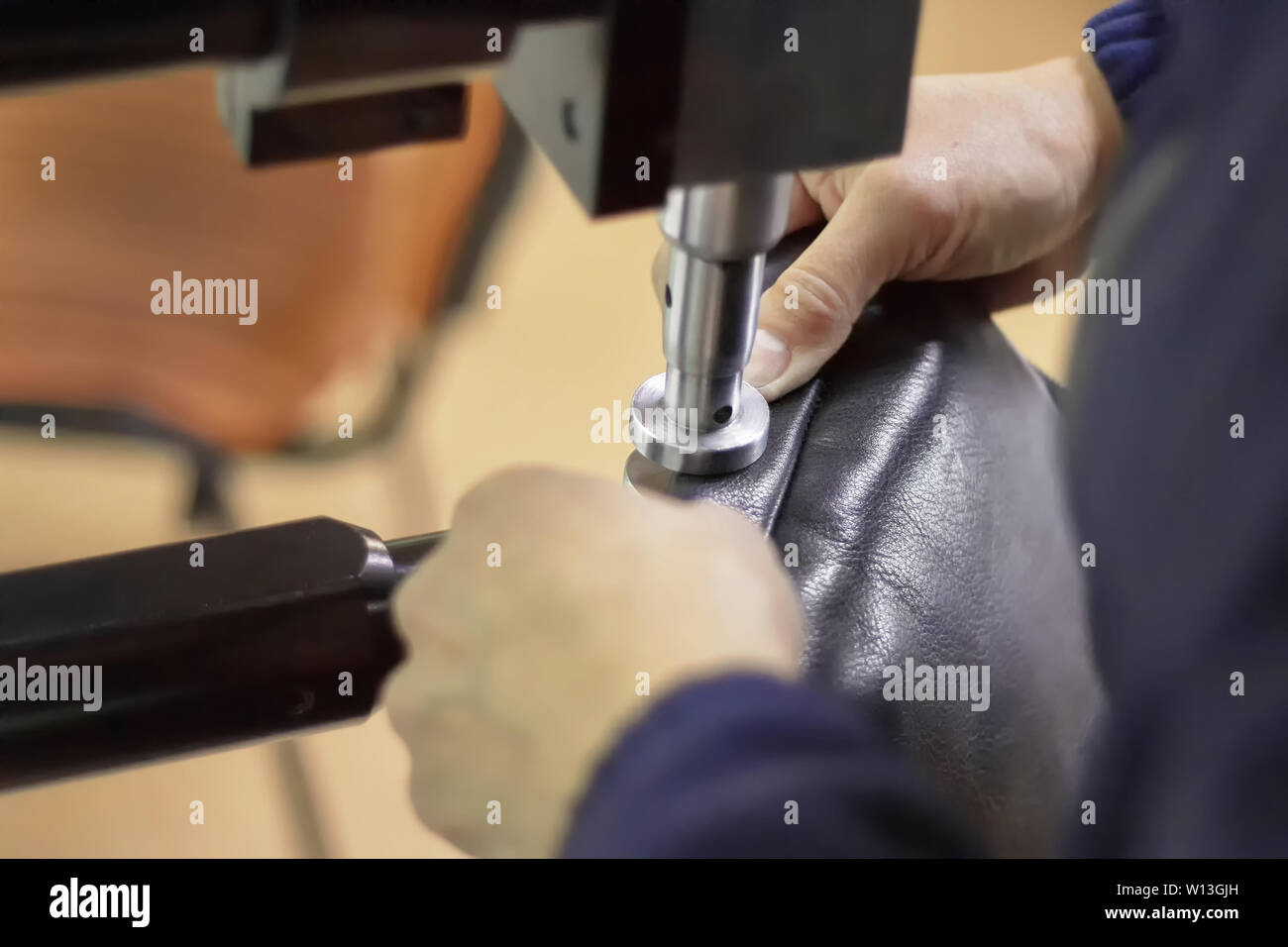 Maschine in einem Leder Workshop in Aktion mit den Händen arbeiten mit einem Leder Details für Taschen und Schuhe. Leder Handwerk. Stockfoto
