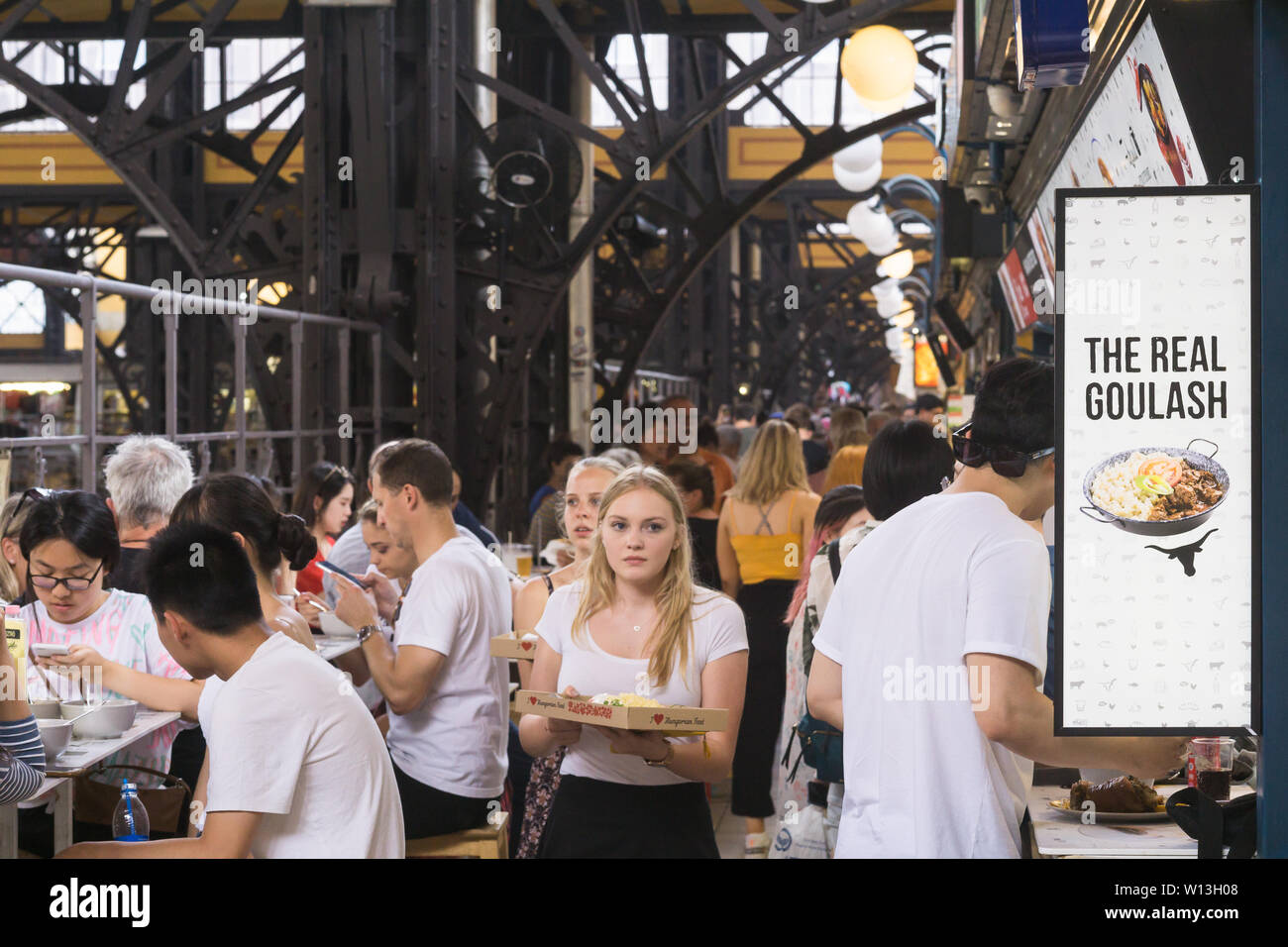 Touristen drängen die Imbissstände in der großen Markthalle in Budapest, Ungarn. Stockfoto
