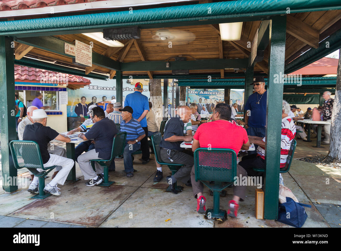 Die älteren Einheimischen Männern sammeln und Dominos auf Maximo Gomez Park/Domino Park an der Calle Ocho in Little Havana, Miami, Florida USA spielen. Stockfoto