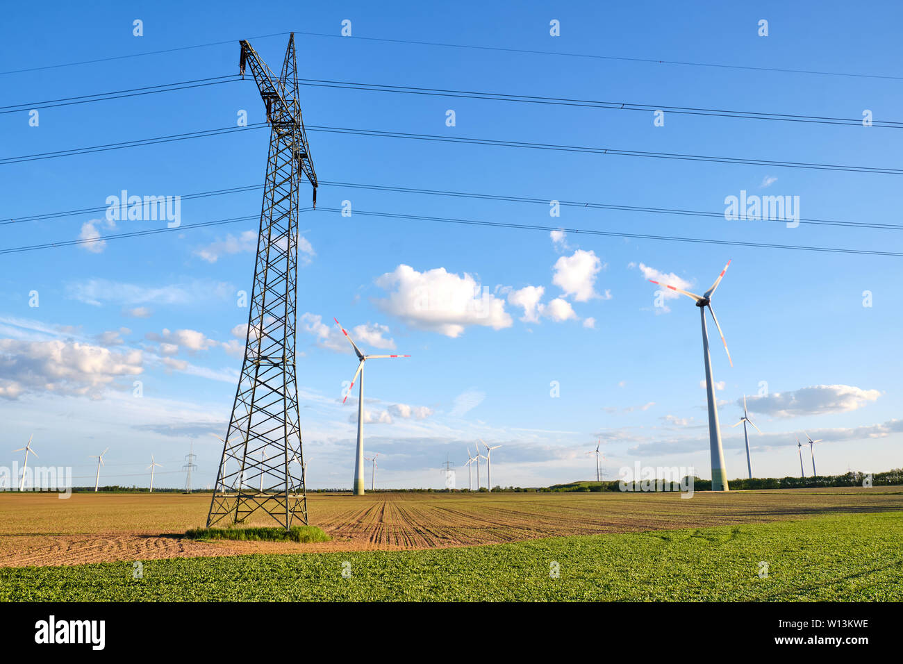 Strom Pylon mit Oberleitung und Windenergieanlagen in Deutschland gesehen Stockfoto