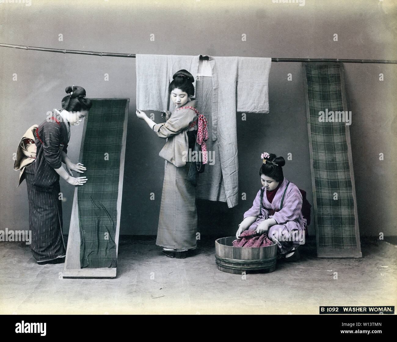 [1890s Japan - Japanische Frauen Waschen Kimono] - Drei Frauen im Kimono und traditionellen Kopfbedeckungen sind die Wäsche machen. Die Frau auf der rechten Seite ist die Wäsche waschen in einem Oke (hölzerne Schaufel), während eine Frau auf der linken Seite ist die Verbreitung einer getrennt Kimono auf einem Holzbrett. 19 Vintage albumen Foto. Stockfoto
