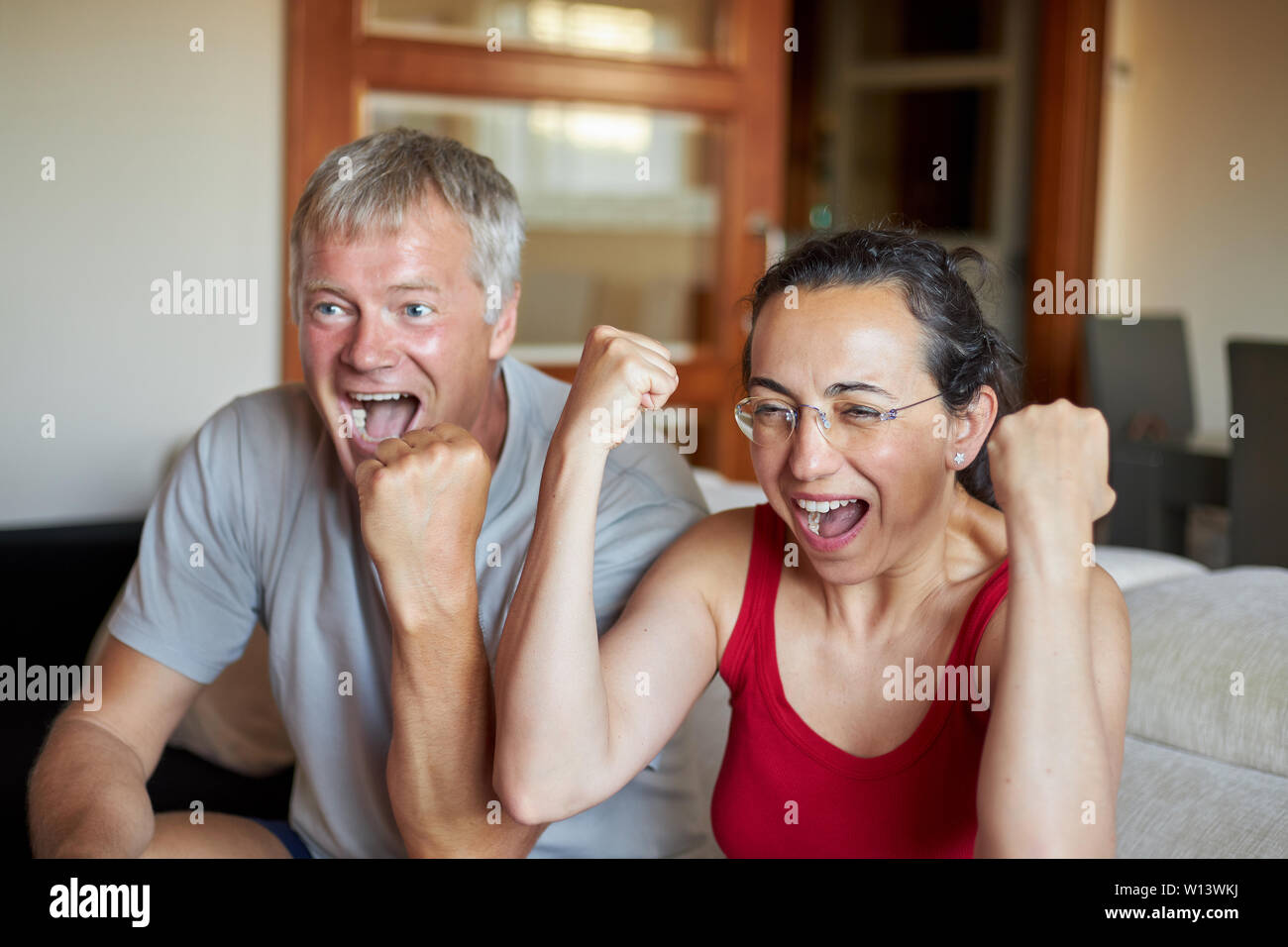 Im mittleren Alter Paare haben einen suchen eine TV zu Hause und glücklich zu gewinnen. Stockfoto