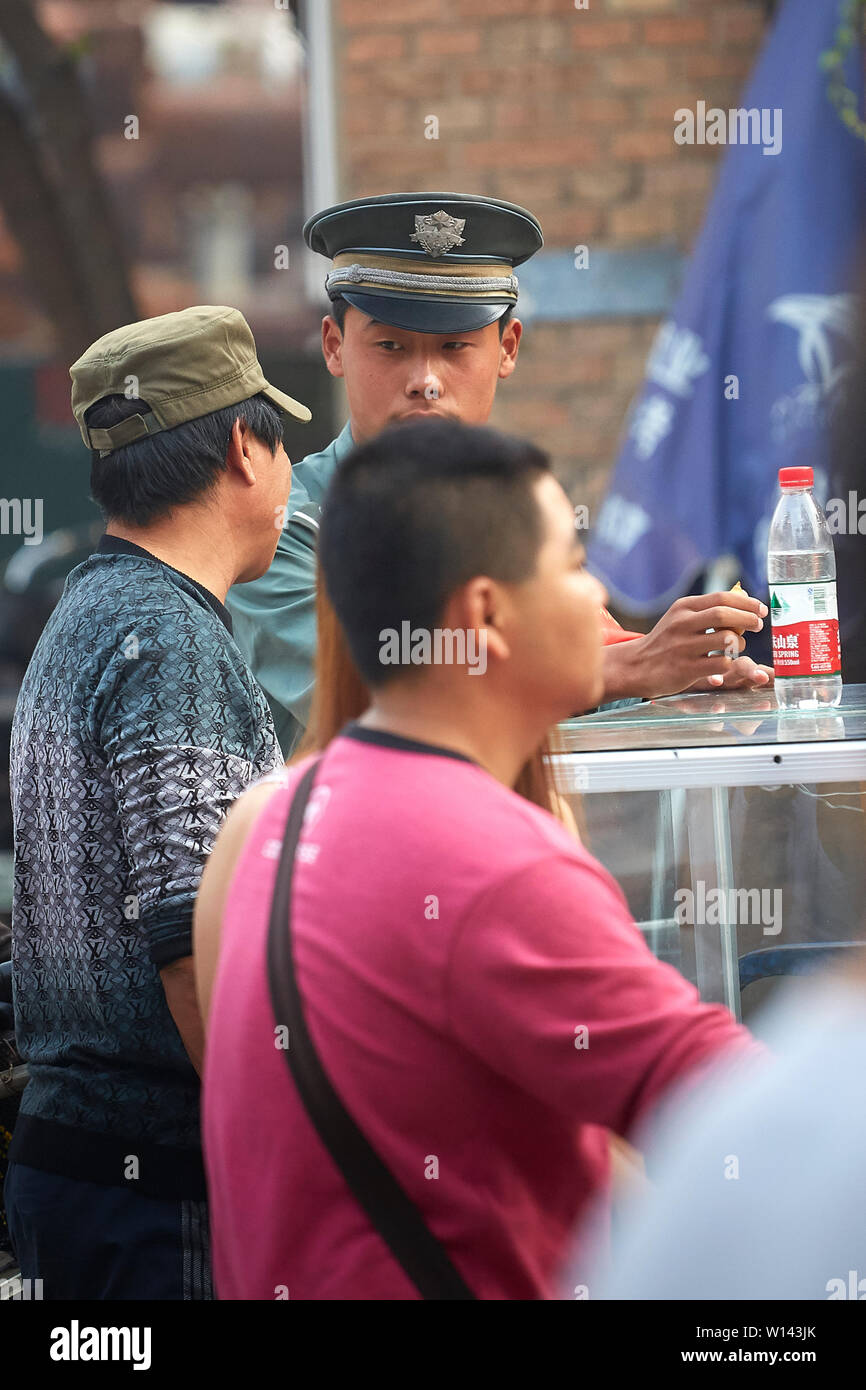 Eine chinesische Polizisten sprechen, während Er nimmt seine Mittagspause In der 798 Art Zone, Peking, Volksrepublik China. Stockfoto