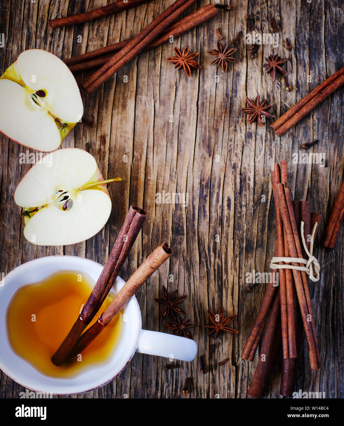 Heißes Getränk (Apple Tee, sider, Punch) mit Zimtstange, Sternanis und Nelke. Saisonale Glühwein trinken auf Holz- Hintergrund. Heißes Getränk und Äpfel für eine Stockfoto