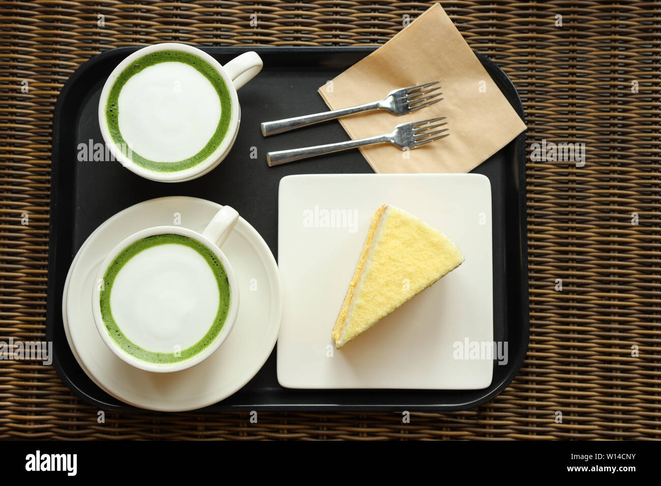 Zwei Tassen Matcha Latte mit einem Stück Kürbiskuchen auf einem Tablett Stockfoto