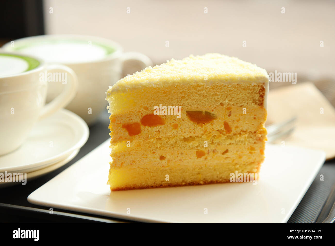 Eine Scheibe von Garten- oder Gemüsekürbissen Kuchen mit zwei Tassen Matcha Latte im Hintergrund Stockfoto