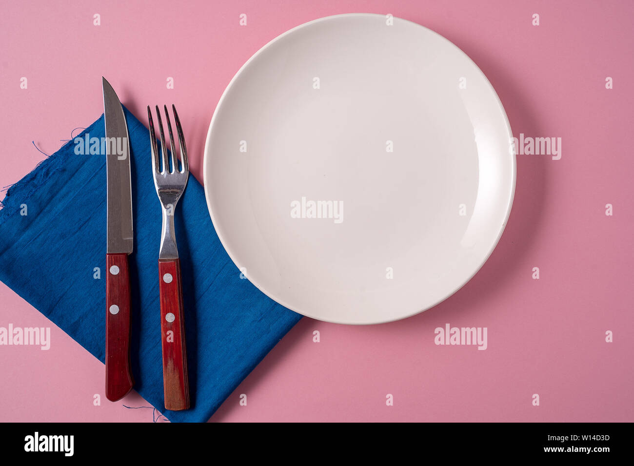 Flach essen Hintergrund mit leeren weißen Teller und Besteck, über rosa Hintergrund. Stockfoto