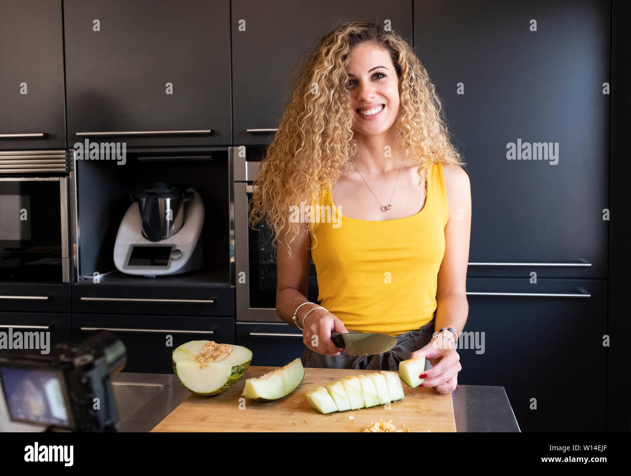 Kaukasische Frau schneiden Melone in einer Küche Stockfoto