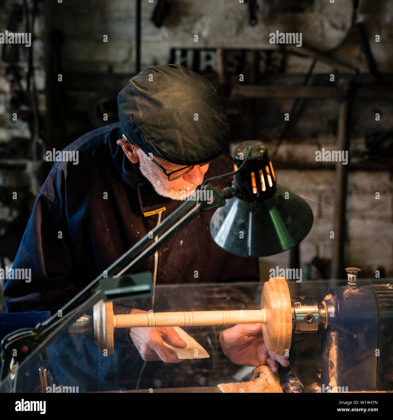 Eine ältere Holz Turner an einer Drehmaschine arbeiten in einem dunklen Werkstatt. Stockfoto