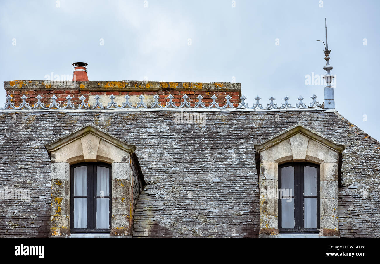 Dachgauben auf Schiefer Dach und orange Schornsteinen. Rochefort-en-Terre, Bretagne Stockfoto